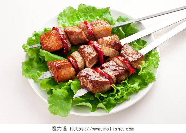 白色背景的烤串和生菜用白色盘子在绿叶上烤肉和蔬菜.